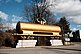 A golden tank wagon for transporting liquids such as mineral oil is decorated with a horizontal euro currency sign, which transforms the figure into a horned idol. It is located in front of the parking lot outside the park grounds and is the first sculpture that invites you to visit. 