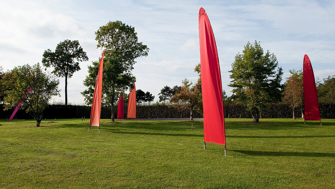 Sails mounted on tilting poles rise up at the rear of the pheasant garden. They move in the wind. 