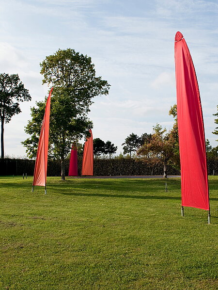 Sails mounted on tilting poles rise up at the rear of the pheasant garden. They move in the wind. 