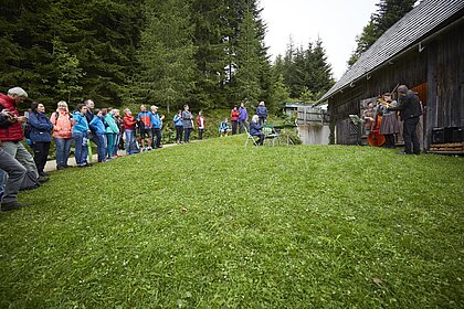 Die Crossfiedler spielen vor Besucherinnen, dahinter befindet sich der Holzschupfn. 
