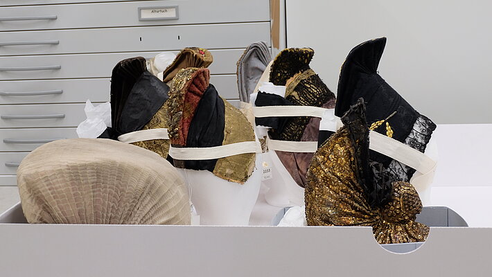 Blick in Lagerraum eines Museums - in Schachtel befinden sich steirische Hauben, die konservatorisch gut versorgt mit säurefreiem Papier gelagert sind.