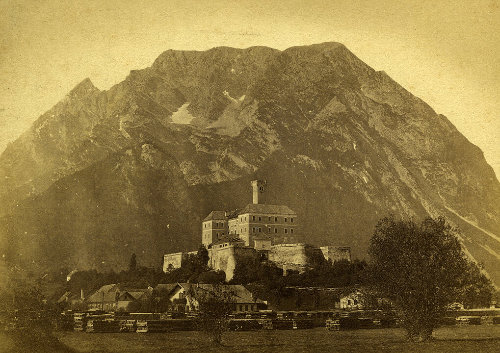 
Old photograph of Trautenfels Castle. The castle stands in front of Mount Grimming. The photo is colored yellow.