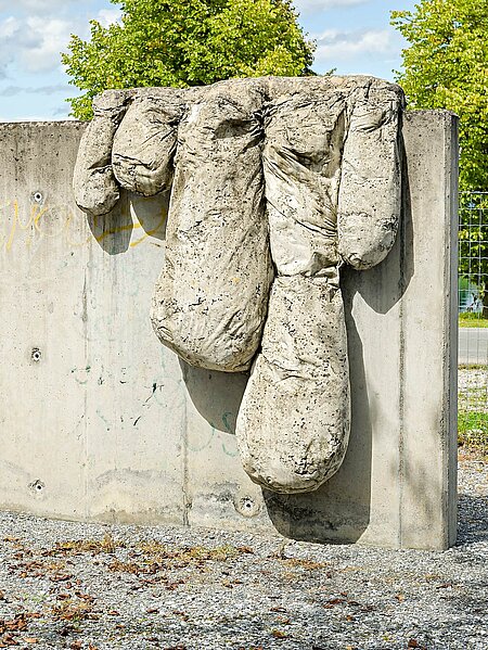 The sculpture by the painter Bohatsch is a vertical, smooth concrete slab with "drops" of concrete hanging down. These resemble fingers and are intended to simulate the paint slowly creeping across the canvas.