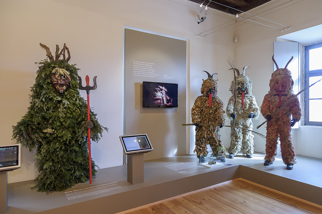 Ausstellungsansicht von einem Raum in dem vier Faschingsfiguren (Miasteufel und Grassteufel) stehen.