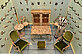 In a showcase are several pieces of furniture and a mannequin wearing a striped dress. The furniture is covered with green velvet and is otherwise made entirely of antler and horn.