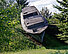 A concrete sculpture in the shape of a real boat appears to float on the hilly landscape o f the sculpture park.