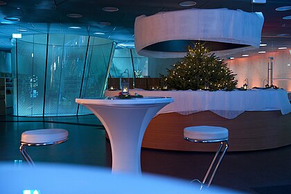 The foyer in the Joanneumsviertel is decorated for Christmas with a Christmas tree and bar tables.