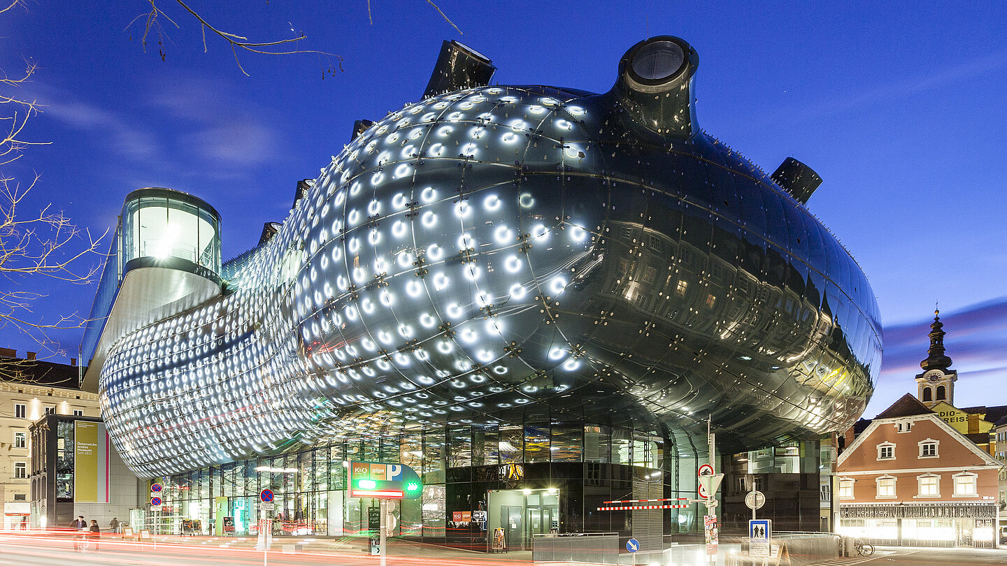 Ansicht des Kunsthaus Graz bei Nacht. Die BIX-Fassade leuchtet.