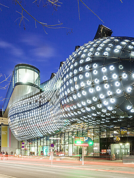 Ansicht des Kunsthaus Graz bei Nacht. Die BIX-Fassade leuchtet.