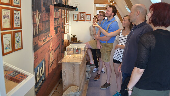 Menschen im Museum, eine Person zeigt auf die Wand