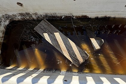Flax in einer alten Badewanne in braunem Wasser liegend, von Brett beschwert.
