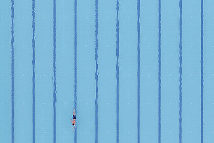 Von oben eröffnet sich der Blick auf ein stilles, menschenleeres Hallenschwimmbad.