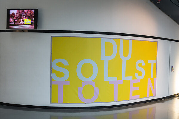 Blick auf das gelbe Banner der Installation "Du sollst töten"