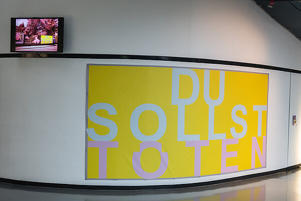 Blick auf das gelbe Banner der Installation "Du sollst töten"