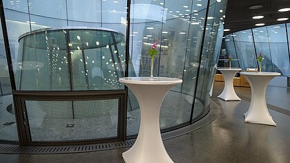 In the foyer of the Joanneumsviertel there are high tables with flowers in vases.