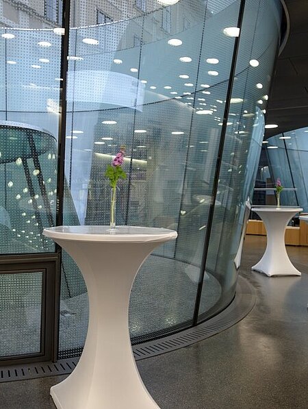 In the foyer of the Joanneumsviertel there are high tables with flowers in vases.