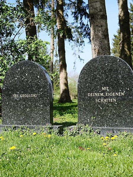 Two gravestones made of smooth stone. The inscription on the first: "Be patient". The inscription on the second: "With your own shadow" [inscriptions are translated from German].