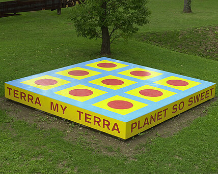 Die Skulptur ist eine Plattform mit der Aufschrift "TERRA MY TERRA/PLANET SO SWEET/I CAN FEEL YOU/UNDER MY FEET".