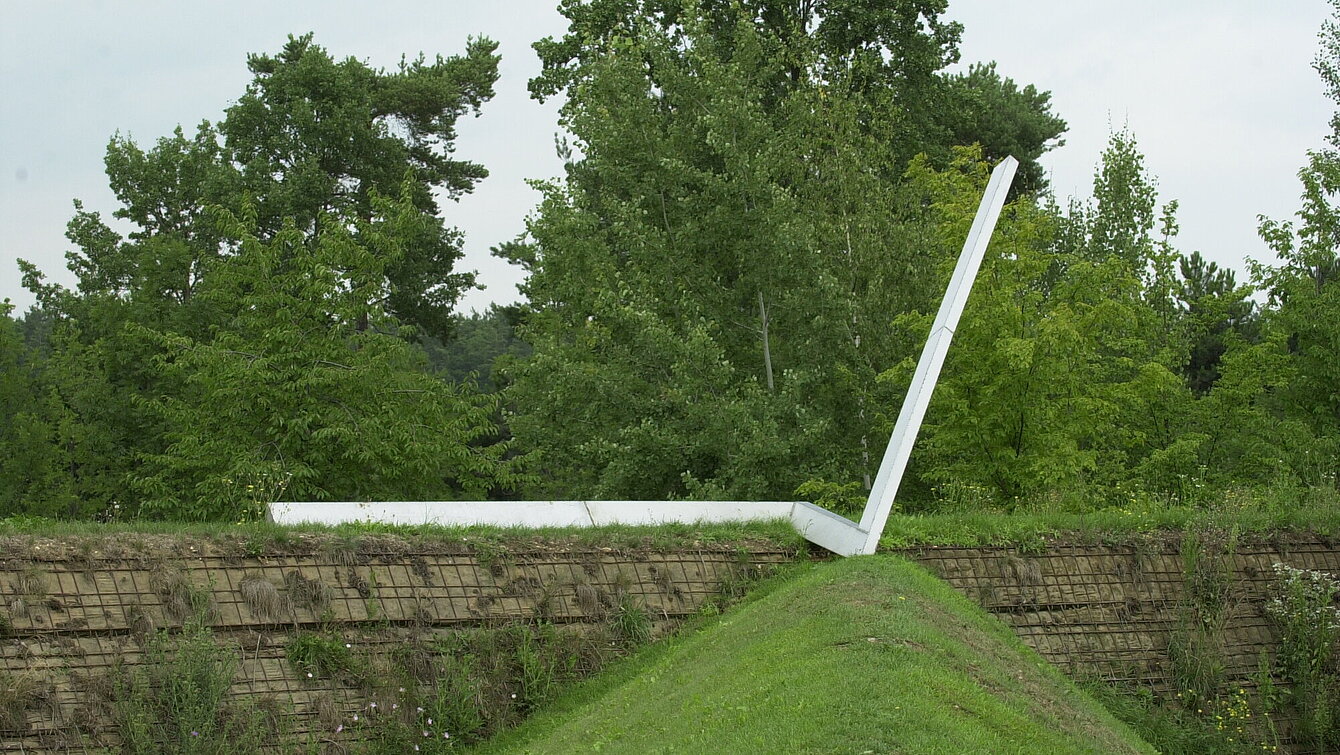 Die Skulptur „Jetzt“ ist eine zweifach abgewinkelte Stahlschiene am oberen eine eines Hanges. Sie stellt eine Zeitachse oder ein Diagramm der persönlichen Entwicklung dar und weist auf Richtungsänderungen hin.