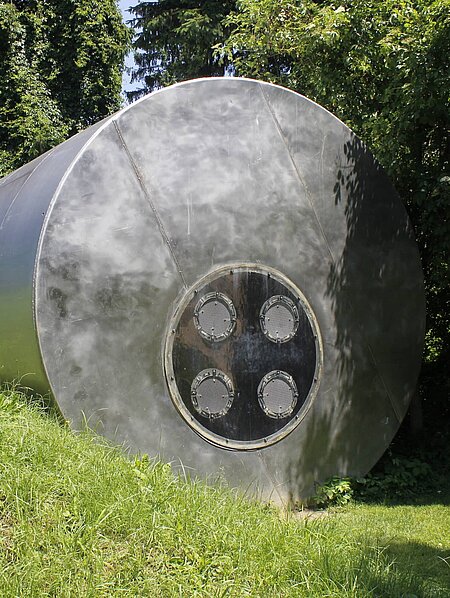 A former steel water silo (11 m long, 4 m in diameter) was reinterpreted by media artist and musician Pinter. It forms the basic structure of this sculpture. Eight integrated bass loudspeakers transform the silo into a musical instrument. The low frequency ranges generate pressure waves that make the sound not only audible but also physically tangible.