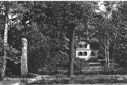 The park of the Rosegger-Museum from the street with the Mauracher-statue and museum in the background, black and white.