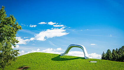 Weitwikliges Panoramabild mit Blick auf die Skulptur "Die Erdkugel als Koffer" und "Sole d'acciaio".