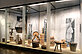 Large glass display case. In it are many objects made of wood, which are needed for milk processing. E.g. buckets, stools and a butter churn.