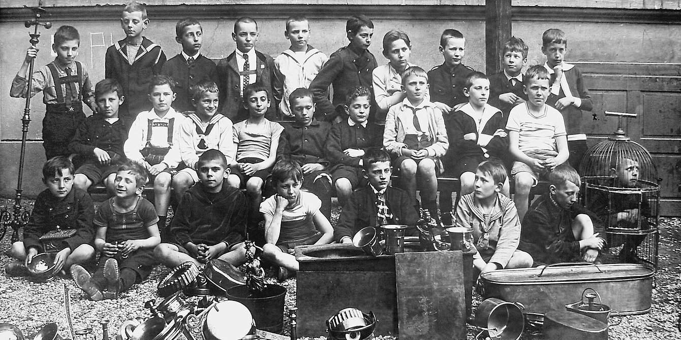 Eine Gruppe von Schülern der evangelischen Schule posiert vor den von ihnen eingesam-melten Metallgegenständen in Graz, o.J. Fotograf unbekannt, Leihgabe: Stadtarchiv Graz