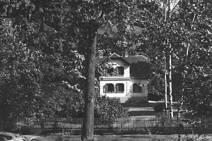 The park of the Rosegger-Museum from the street with the Mauracher-statue and museum in the background, black and white.