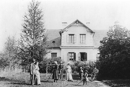 Members of the Rosegger family playing croquet in the garden in front of the summer house, black and white.