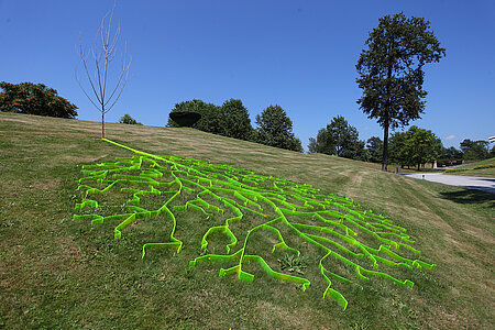 Installation eines abgestorbenen Baumes mit Schatten aus neongrünem Plexiglas. 