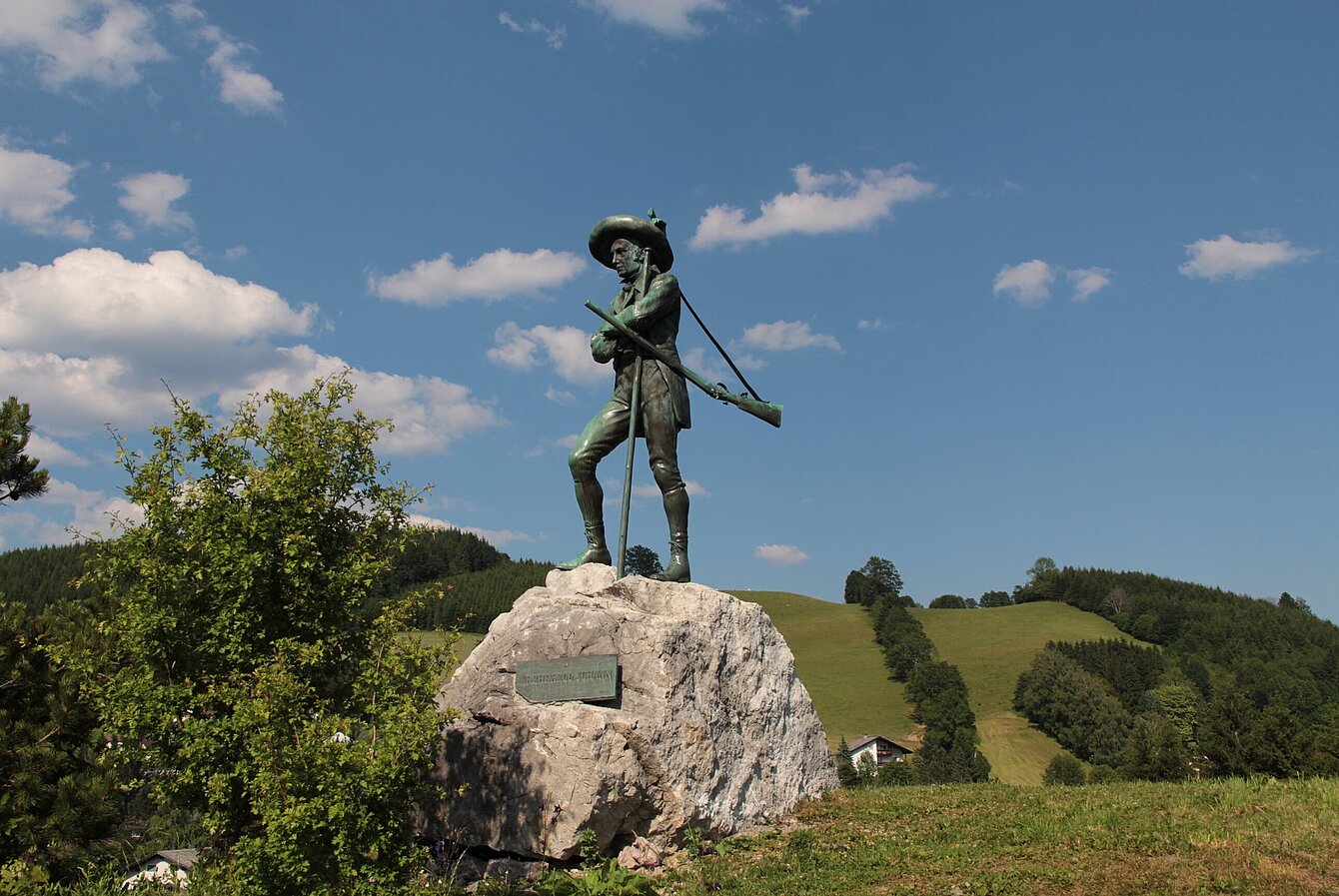 Erzherzog Johann Statue aus Eisen  auf Fels in grüner Wiese vor Mariazell