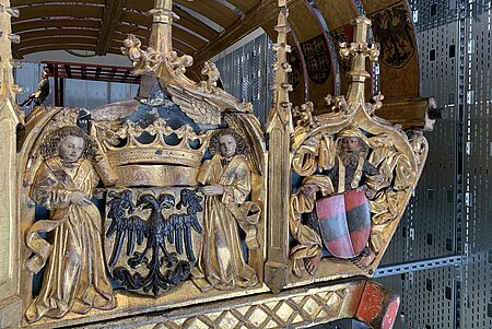 Zu sehen ist eine Detailansicht des Prunkwagens von Friedrich III.  Das Wappen des Herzogtums Steiermark und das Wappen des Heiligen Römischen Reichs stehen im Zentrum.