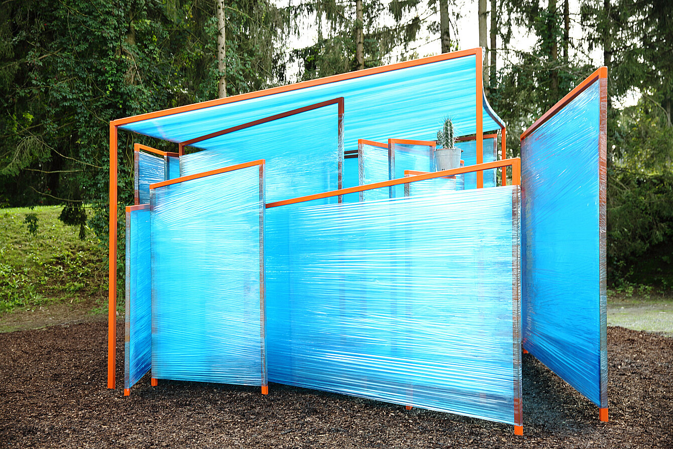 Skulptur aus orangen Metallstangen und blau-transparenter Kunststofffolienummantelung. 