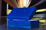 Man sieht eine blaue Box von hinten, aus der bunte Strahlen und Licht herauskommen. Es wirkt sehr geheimnisvoll und man bekommt Lust, in die Box hineinzuschauen.