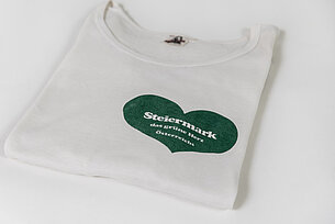 Zu sehen ist ein weißes T-Shirt, bedruckt mit dem grünen Herz der Steiermark .