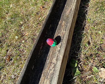 Ein Ei rollt durch eine Holzrinne. Es ist ein Spiel zu Ostern. 