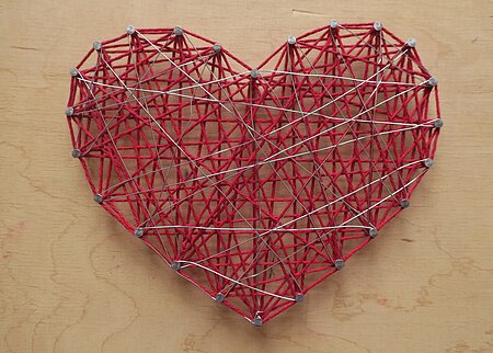Nagelbild auf Holzbrett mit roter Fadenspanntechnik in Herzform