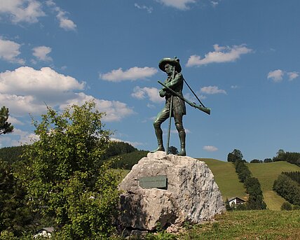 Erzherzog Johann Statue aus Eisen  auf Fels in grüner Wiese vor Mariazell