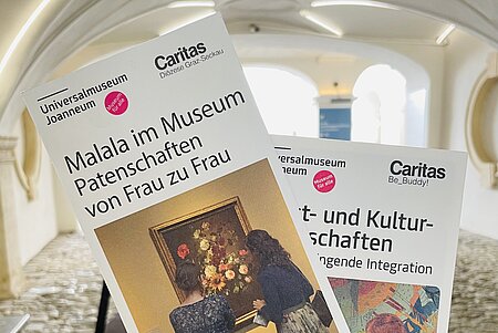 Zu sehen sind Flyer der Caritas-Kooperationen im Innenhof des Museums für Geschichte.