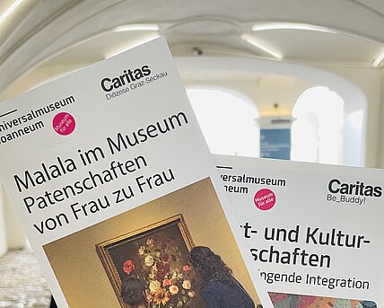 Zu sehen sind Flyer der Caritas-Kooperationen im Innenhof des Museums für Geschichte.