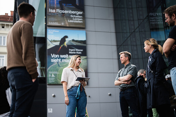 Mehrere Personen hören einer Kunstvermittlerin zu