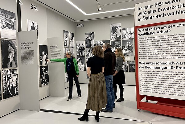 Gruppe in der Ausstellung "Alles Arbeit" Zu sehen ist eine Vermittlerin mit einer Erwachsenengruppe in der Ausstellung "Alles Arbeit".
