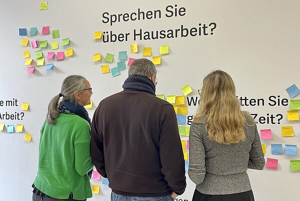 Mitmachwand in Alles Arbeit Zu sehen sind drei Personen im letzten Ausstellungsraum von "Alles Arbeit".