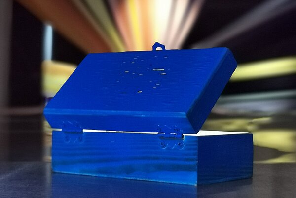 Man sieht eine blaue Box von hinten, aus der bunte Strahlen und Licht herauskommen. Es wirkt sehr geheimnisvoll und man bekommt Lust, in die Box hineinzuschauen.